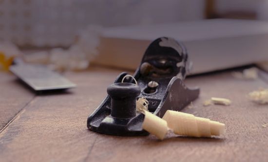 A black hand plane sitting on a workbench with wood shavings