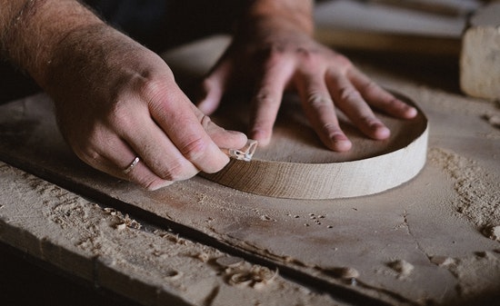 A woodworker feeling the edges of a smoothed piece of wood that has been measured with a moisture meter