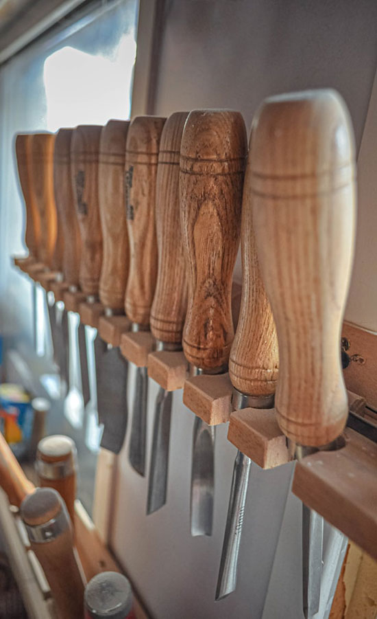 An assortment of chisels mounted in a row on a wall