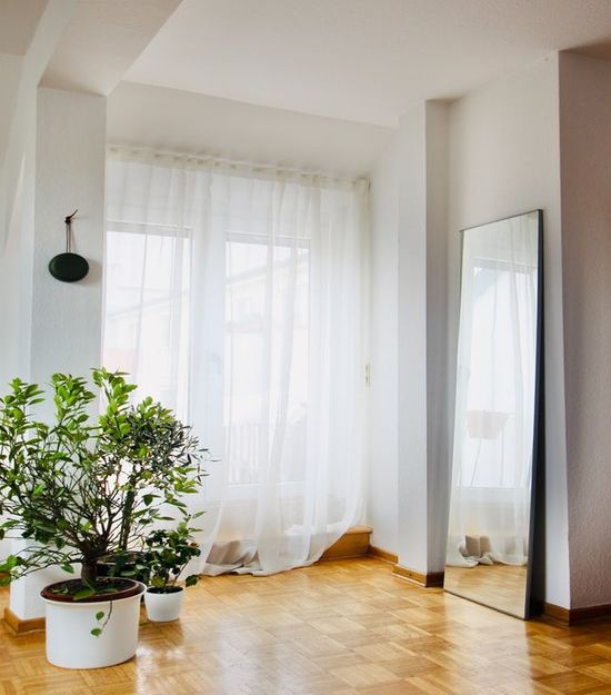 A window with a curtain to decrease the wood floor's exposure to sunlight