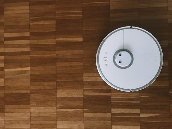 A hardwood floor with a round, white cleaning robot