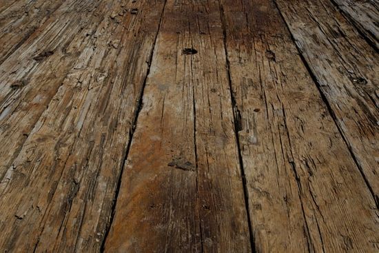 An old, damaged floor with wood that is chipping off