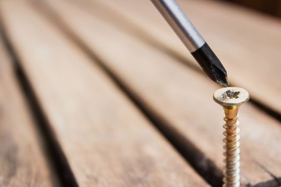 A screw being driven into boards of wood