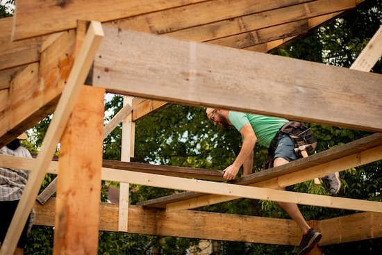 A man building a house frame, which doesn't require kiln-dried wood
