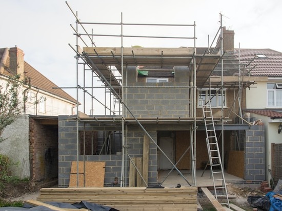 Construction site of a home with stacks of wood that need to be measured with a moisture meter