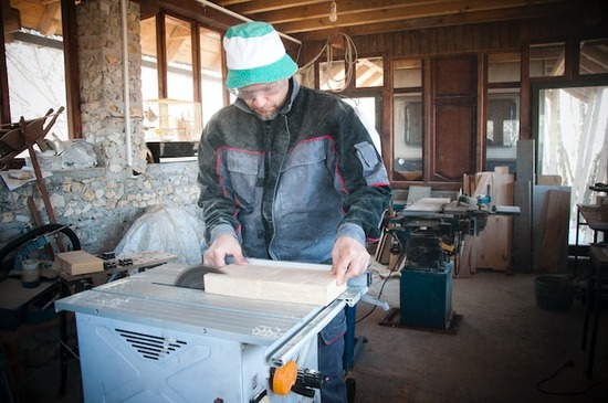 A woodworker cutting a piece of wood with a tablesaw