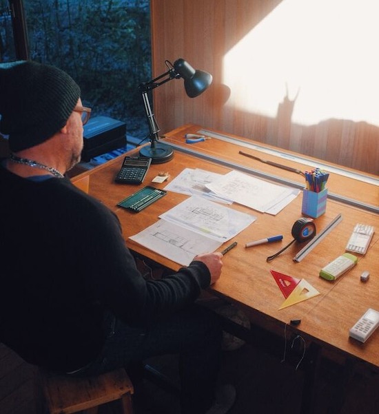 A man sitting at a desk and drawing plans