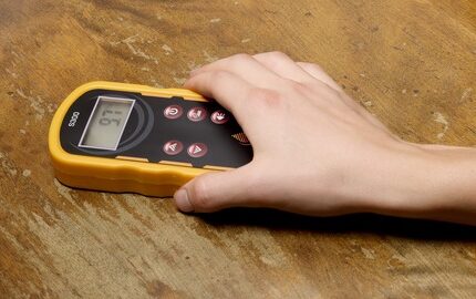 A home inspector placing a moisture meter on damaged wood