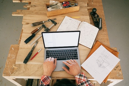 A woodworker working on a laptop and preparing to buy lumber for a woodworking project