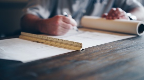 A hand writing out woodworking plans