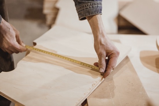 Hands measuring a piece of plywood with a tape measureHands measuring a piece of plywood with a tape measure