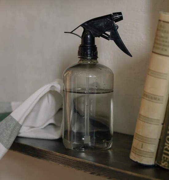 A clear spray bottle filled with water