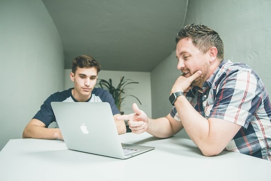 Two men looking at woodworking resources on a laptop