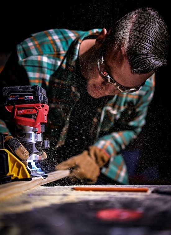 A woodworker wearing protective eye glasses while cutting wood with a miter saw