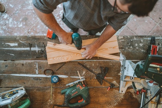 A woodworker drilling holes with a power drill