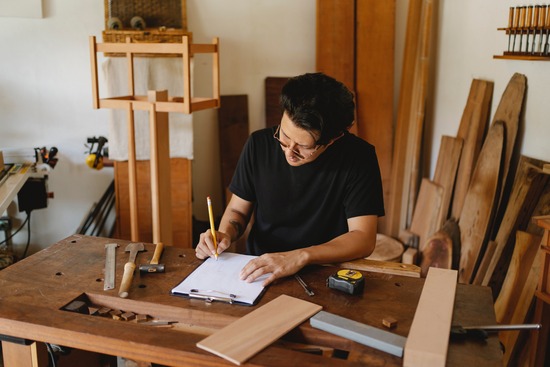 A woodworker sitting at a table and drawing a furniture design