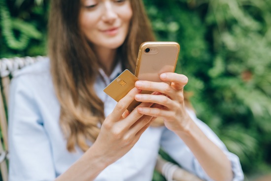 A woman using her phone to shop for wooden furniture