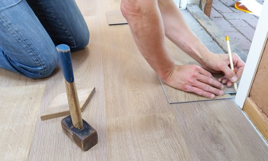 A person making marks with a pencil while installing a hardwood floor