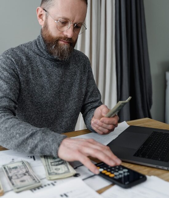 A man counting money and using a calculator