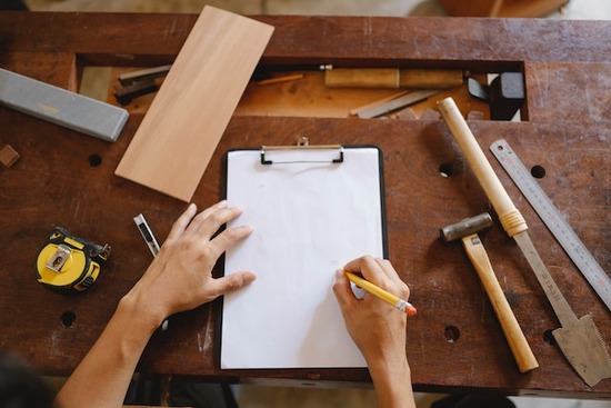 A hand sketching a plan for a piece of wood furniture