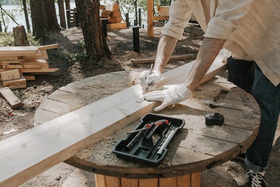 A woodworker carefully tracing lines for cutting on a piece of wood to prevent waste