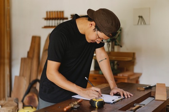 A woodworker in his shop taking notes before starting a woodworking project