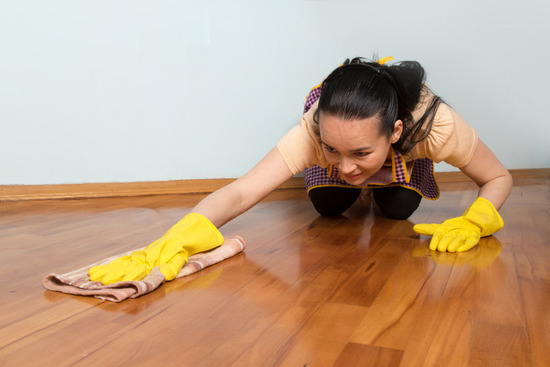 A women with yellow gloves cleaning a laminate floor
