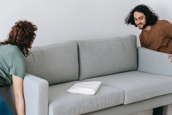 A couple moving a couch in preparation for floor installation