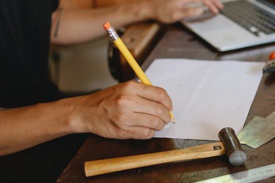 A hand writing notes on a floor quality assurance plan 