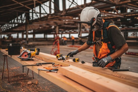 A construction worker drilling into a piece of wood