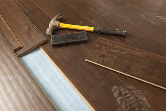Installation tools on top of engineered wood floorboards that are being installed