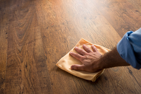  A hand wiping a hardwood floor with a microfiber cloth