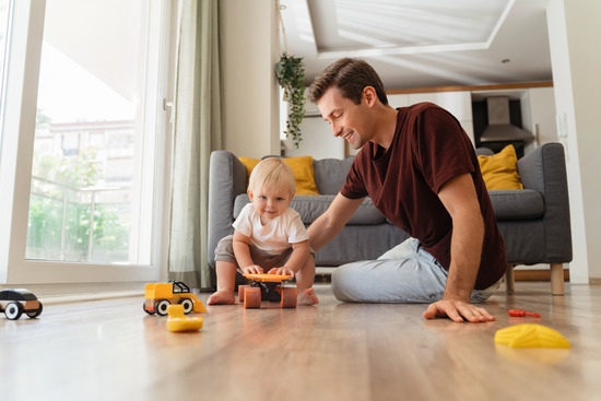 A father and son playing with toys on a wood floor