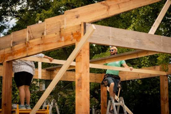 Two people building a wood frame for a small building