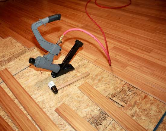 A nail gun sitting by a partially-installed wood floor
