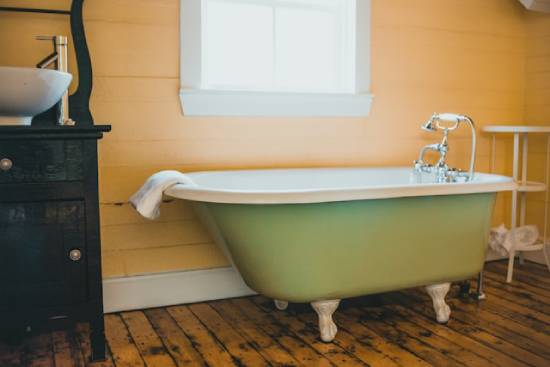 A bathroom with a hardwood floor covered in black mold. 
