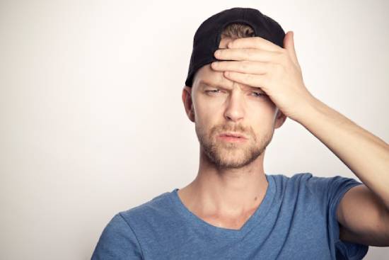  Man resting his hand on his forehead as he suffers from a headache.