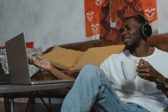 A man sitting on the floor, watching videos on his laptop with an amused smile