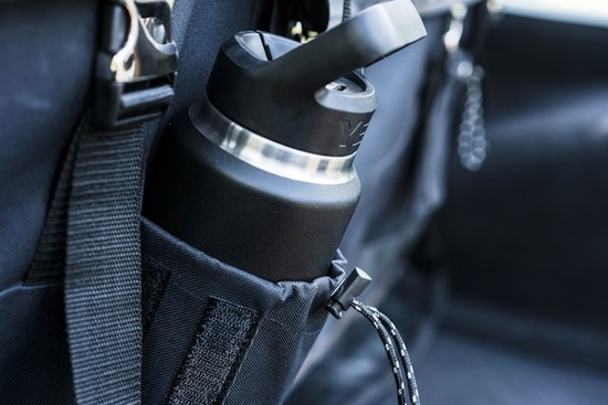 A black insulated water bottle held in a backpack