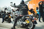 A man on a motorcycle wearing a leather jacket with the words, 'Harley Davidson' on the back