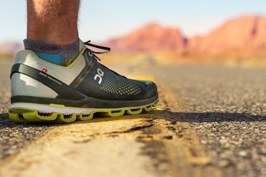 Man standing on a paved road wearing athletic sneakers