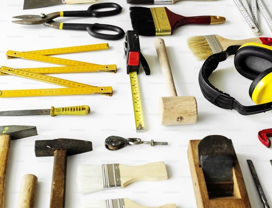 An assortment of woodworking tools like measuring tapes, hammers, and paintbrushes.