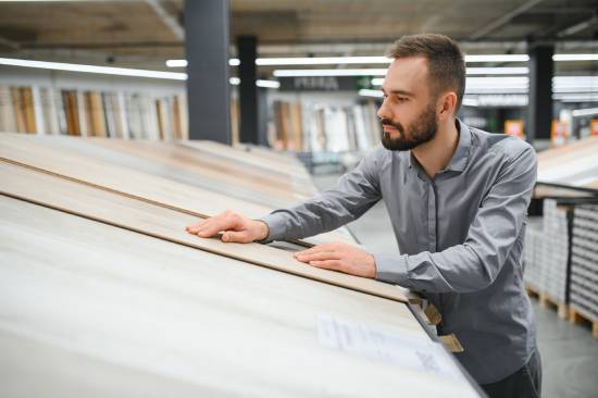 A man examining a piece of laminate flooring at the store